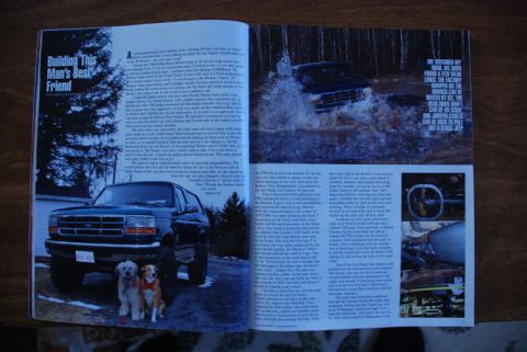 1996 Ford Bronco - A dark blue Ford Bronco is shown driving through a muddy water crossing, kicking up a large splash.