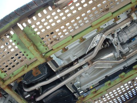 2007 Ford Mustang - The underside of a vehicle reveals its exhaust pipes and transmission components, with some visible text on a part.