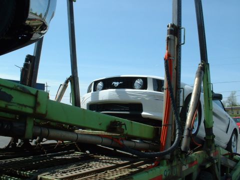 2007 Ford Mustang - A white 2007 Ford Mustang is loaded onto a car carrier, seen from the front.