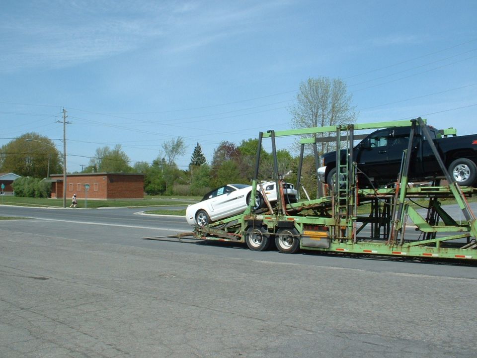 2007 Ford Mustang on a car carrier truck with a black pickup truck above it