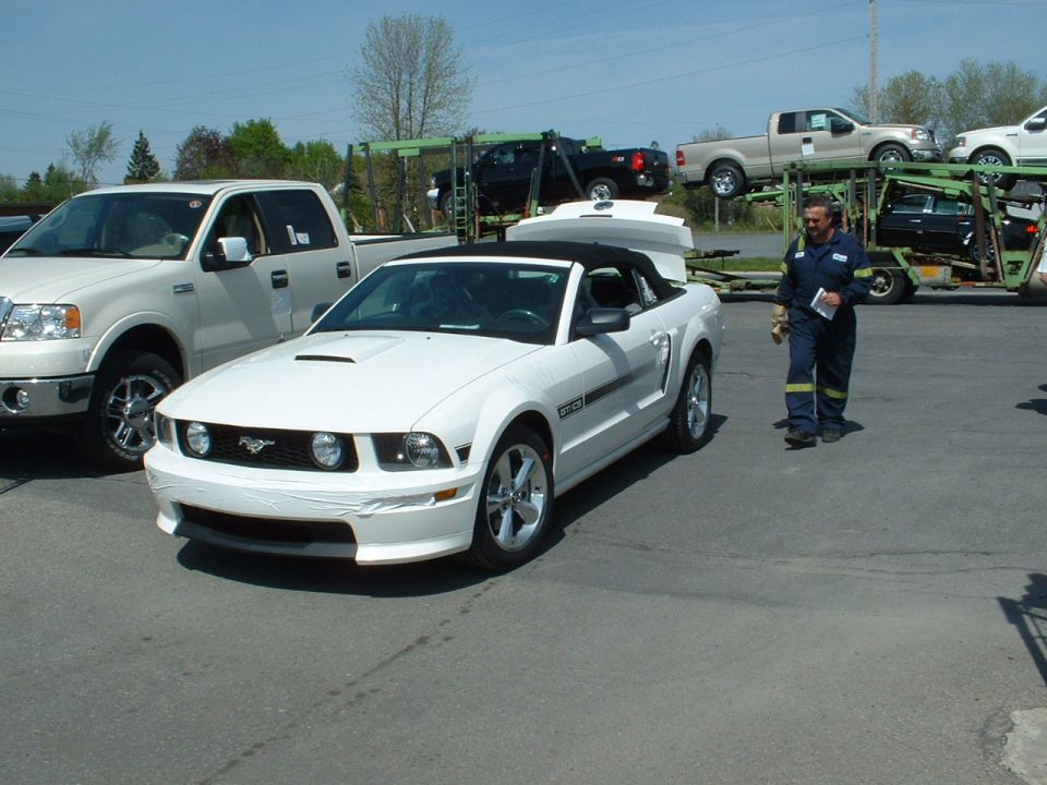 White 2007 Ford Mustang convertible parked next to a pickup truck