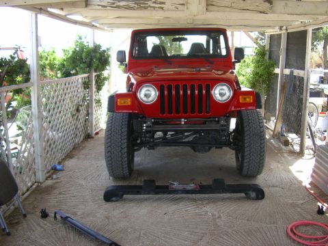 2004 Jeep TJ - Front view of a red Jeep Wrangler parked under a covered area.