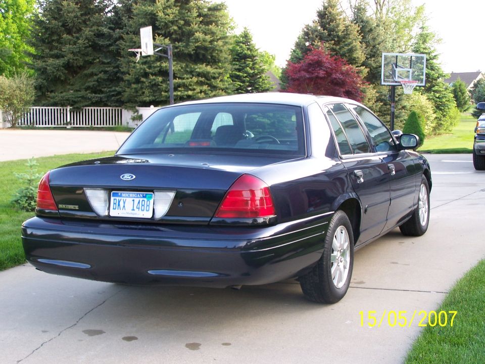 Dark blue 2003 Ford Crown Victoria parked on driveway, rear view. Michigan license plate BKX 1488