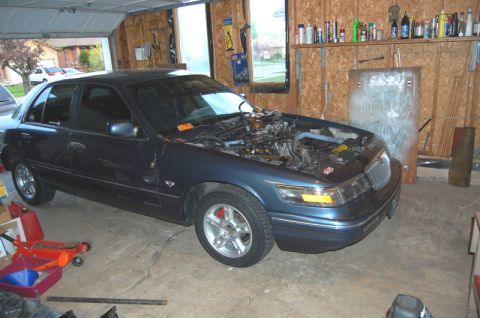 1985 Mercury Grand Marquis - Sedan in a garage, hood open, showing engine components and red brake calipers.