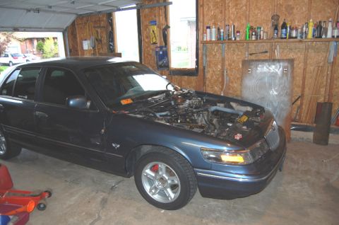 1985 Mercury Grand Marquis - A dark blue sedan sits in a garage with its hood open, revealing the engine compartment.