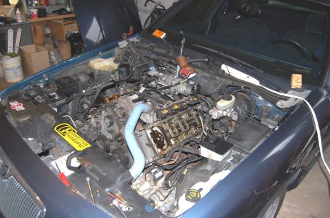 1985 Mercury Grand Marquis - The engine bay of a blue car is shown with various tools and a yellow sticker that reads 'Competition Engineering'.