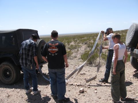 2004 Jeep TJ - A group of people prepare to use tow straps with a Jeep TJ in a desert landscape.