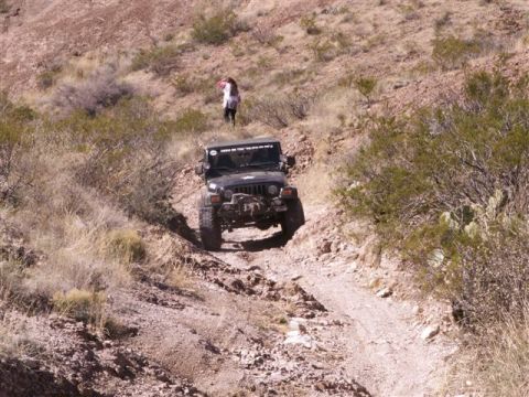 2004 Jeep TJ - A black 2004 Jeep TJ navigates a , dusty trail in a desert landscape.