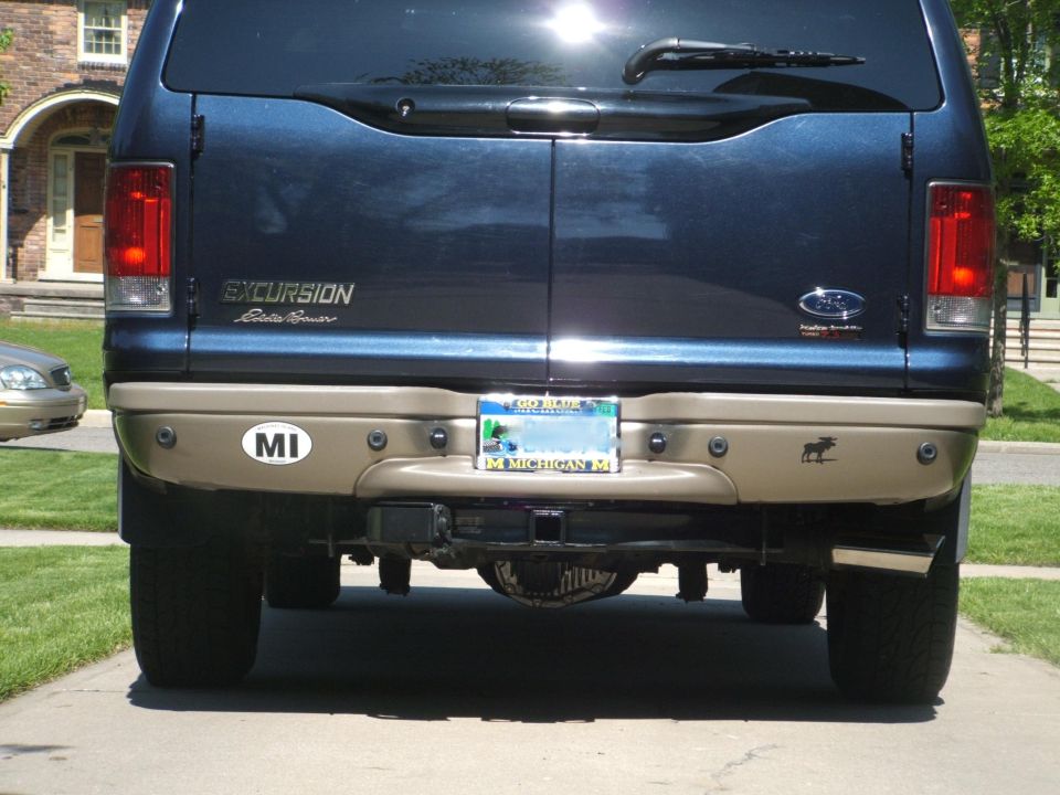 Rear of dark blue Ford Excursion SUV with MI sticker, moose decal, and Michigan plate.