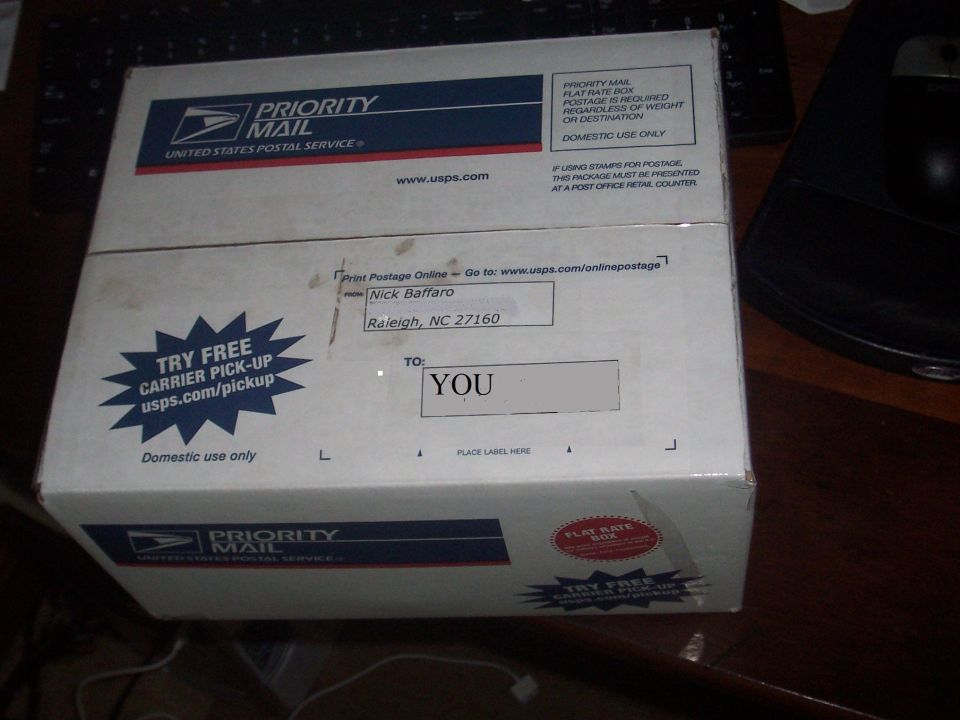 White USPS Priority Mail box with blue and red stripes, addressed to YOU from Nick Baffaro in Raleigh, NC