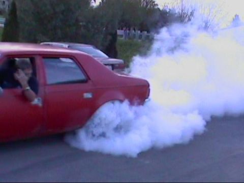 1901 Honda Odyssey - A red car performs a burnout, creating a large cloud of smoke.