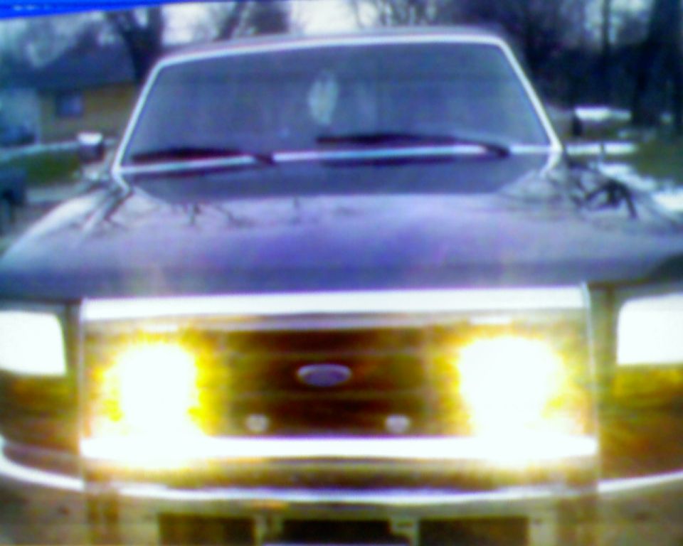Head-on view of a dark Ford truck with headlights glaring over the oval grille