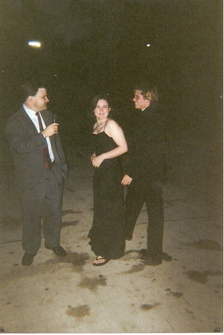 Three people in formal wear stand on a paved surface at night. A watermark reads www.supermotors.net