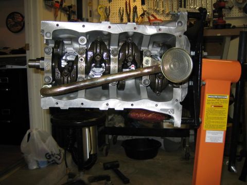 1987 Suzuki Samurai - Engine block assembly, showing the crankshaft and oil pump pickup, mounted on an orange engine stand.