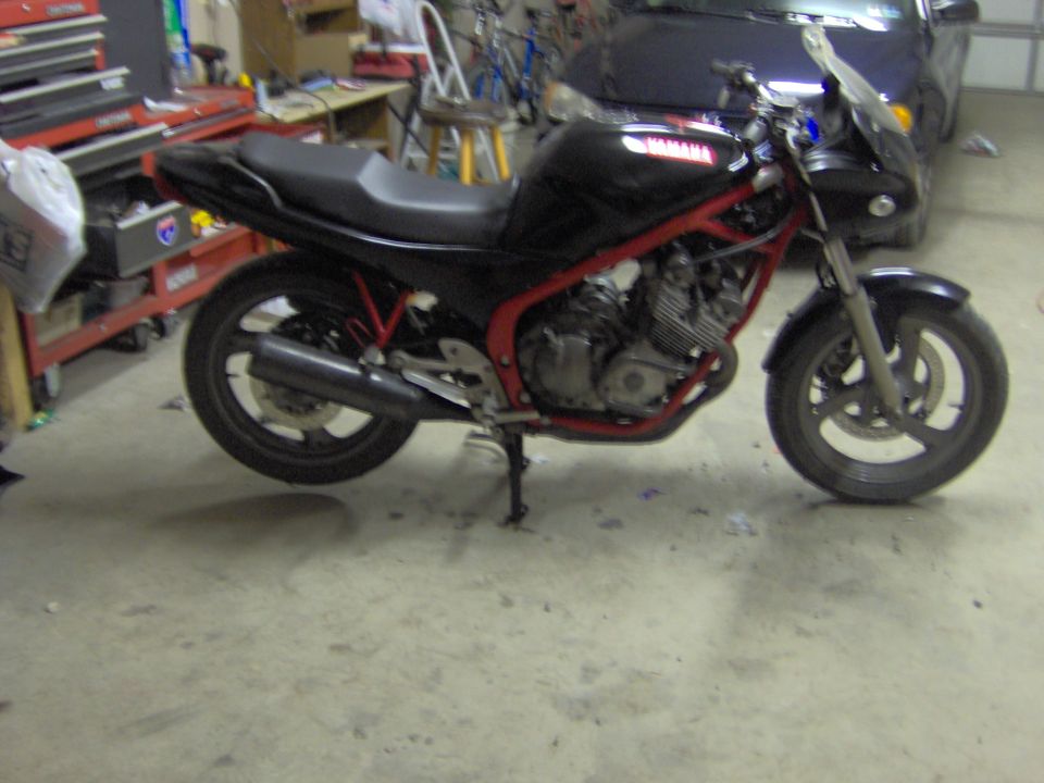 Black Yamaha motorcycle with red frame, side view, parked indoors