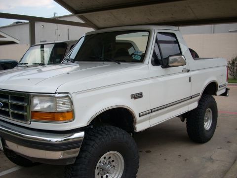 1992 Ford Bronco - This lifted 1992 Ford Bronco is parked under a covered area, with another vehicle partially visible behind it.