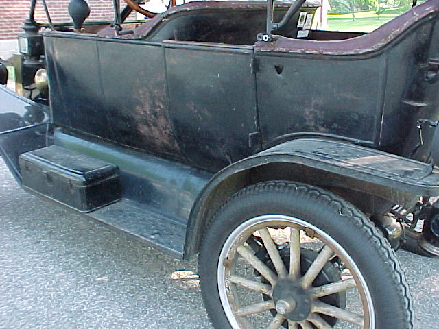 Side view of a black 1913 Ford Model T touring car with wooden-spoke wheels and running board box