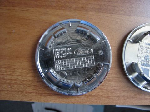 2003 Ford Crown Victoria - Close-up of the reverse side of a Ford hubcap, showing manufacturing details and the brand emblem.