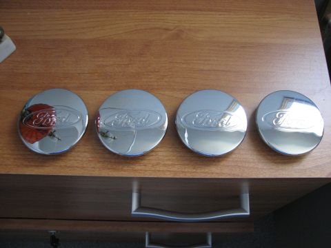 2003 Ford Crown Victoria - Set of four Ford hubcaps displayed on a wooden surface.