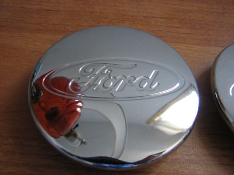 2003 Ford Crown Victoria - A shiny chrome Ford hubcap is shown on a wooden surface.