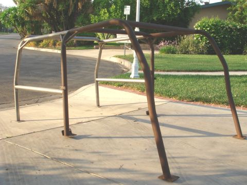 1977 Ford Bronco - A weathered roll cage sits on a concrete surface, suggesting it is a vehicle part.