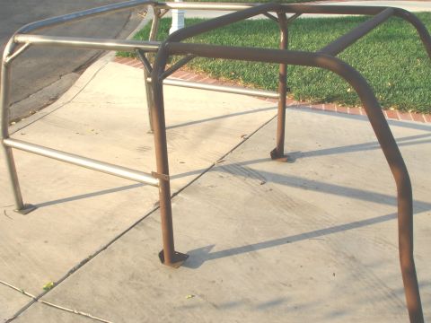 1977 Ford Bronco - Roll cage tubing sections are shown on a concrete driveway with grass in the background.