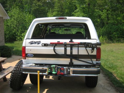 1996 Ford Bronco - Rear view of a white Ford Bronco with a spare tire and mounted jack, parked outdoors.