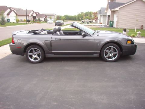 1993 Ford Bronco - This gray convertible is parked on a driveway in front of a suburban house.
