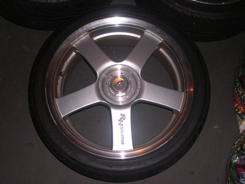 Close-up of a silver five-spoke aftermarket wheel with 'Rz Evolution' text on one spoke