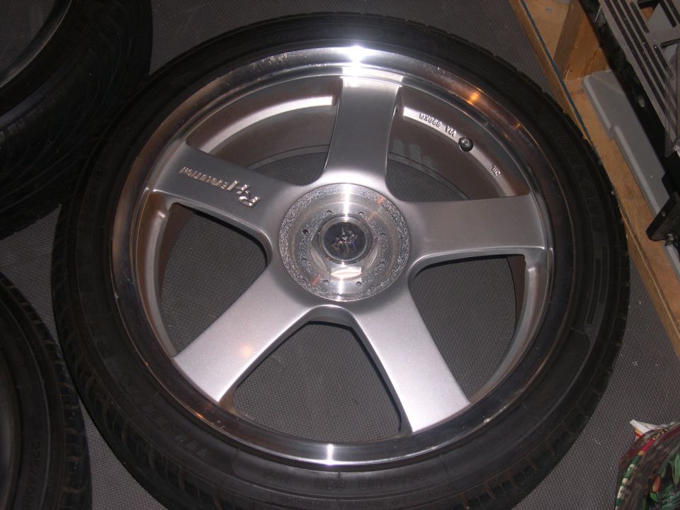 Close-up of a silver five-spoke aftermarket wheel with a tire mounted