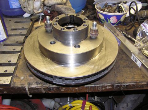 2000 Chevrolet Tahoe - A close-up view of a brake rotor and hub assembly, likely for a truck or SUV, resting on a cluttered workbench.