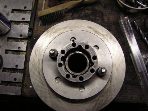 2000 Chevrolet Tahoe - Close-up of a brake rotor and hub assembly with tools on a workbench.