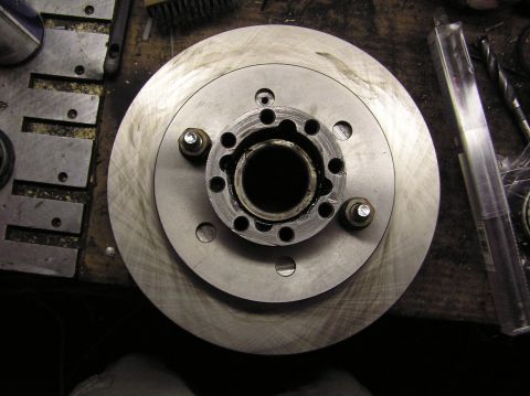 2000 Chevrolet Tahoe - A brake rotor and hub assembly is shown on a workbench, with various tools and parts scattered around.