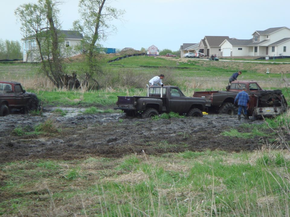 Several pickups and people working in a muddy field
