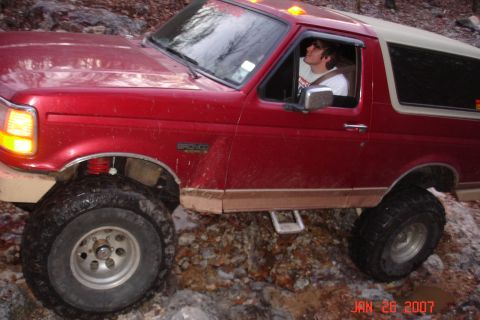 1995 Ford Bronco - 1995 Ford Bronco navigating a rocky trail with a driver inside.