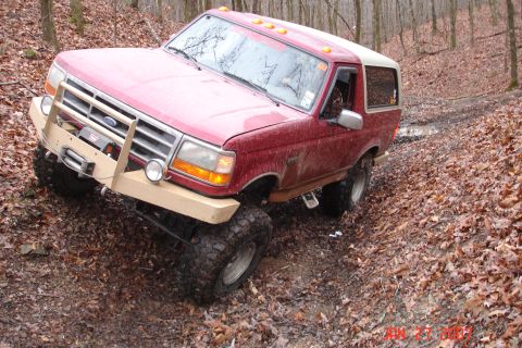 1995 Ford Bronco - This red Ford Bronco navigates a challenging off-road course with its modified bumper and winch.