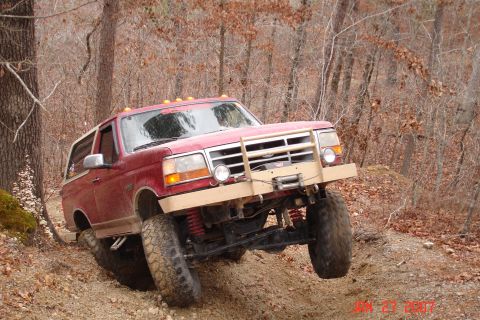 1995 Ford Bronco - This modified Ford Bronco navigates a challenging off-road trail with its tires digging into the loose dirt.