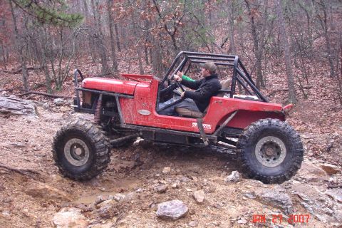 1995 Ford Bronco - A driver navigates a challenging off-road course in a modified red jeep.