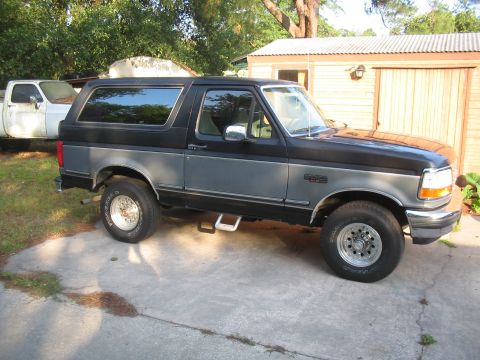 1992 Ford Bronco - This 1992 Ford Bronco is parked next to a white pickup truck in front of a wooden garage.