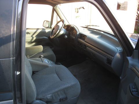 1992 Ford Bronco - The interior of a truck is shown, cloth seats and a dashboard with vents.