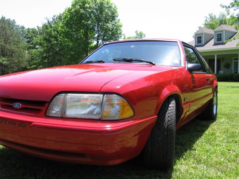 1967 Ford Mustang - A red Ford Mustang GT is parked on a grassy lawn in front of a house.