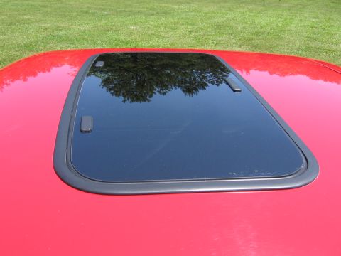 1967 Ford Mustang - Close-up of a car's sunroof with a reflection of trees in the glass.