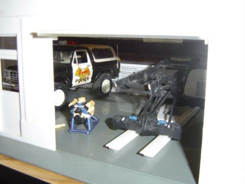 1979 Ford Bronco - A model of a 1979 Ford Bronco painted as a police vehicle sits inside a garage diorama.