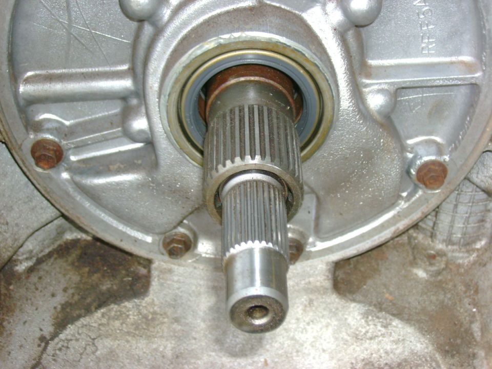 Close-up of a splined shaft extending from a silver metal housing with bolts