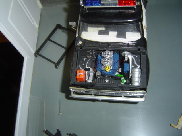 Model police car with hood open showing engine detail, blue engine block, chrome air intake