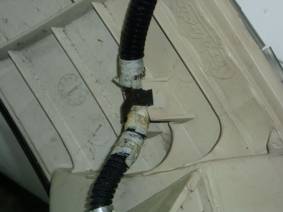 Black ribbed cable with labeled sections clipped to beige plastic trim panel