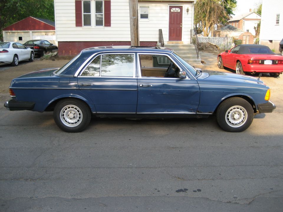 Dark blue Mercedes-Benz W123 sedan parked in side profile on driveway
