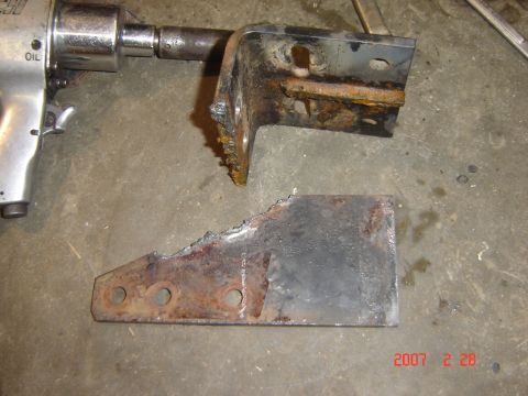 1993 Ford Bronco - A rusted metal bracket and a detached piece lie on the floor next to an air-powered wrench.
