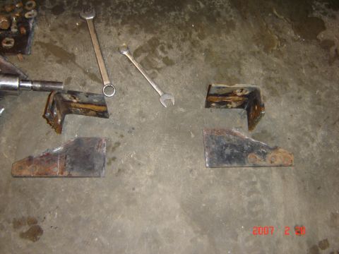 1993 Ford Bronco - Several rusted metal brackets and two wrenches are laid out on a concrete surface.