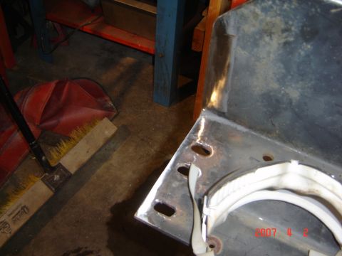 1993 Ford Bronco - A metal bracket with mounting holes and a white strap is shown, with a broom and dustpan in the background.